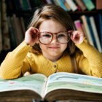 Girl putting on glasses while reading