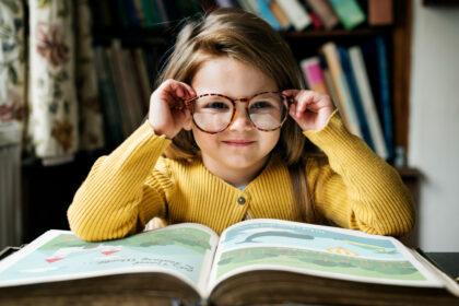 Girl putting on glasses while reading