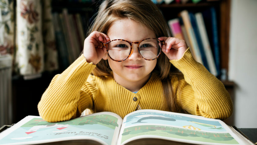 Girl putting on glasses while reading