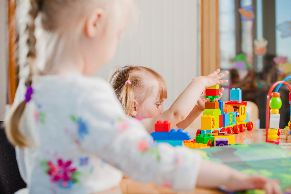 Toddlers playing with colourful building blocks in nursery